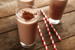 Chocolate lactose free milkshake in glass with cocoa and straws