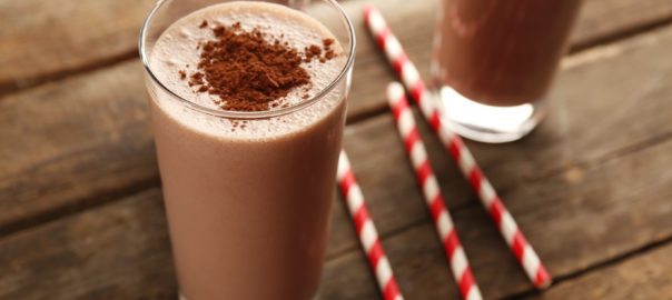 Chocolate lactose free milkshake in glass with cocoa and straws