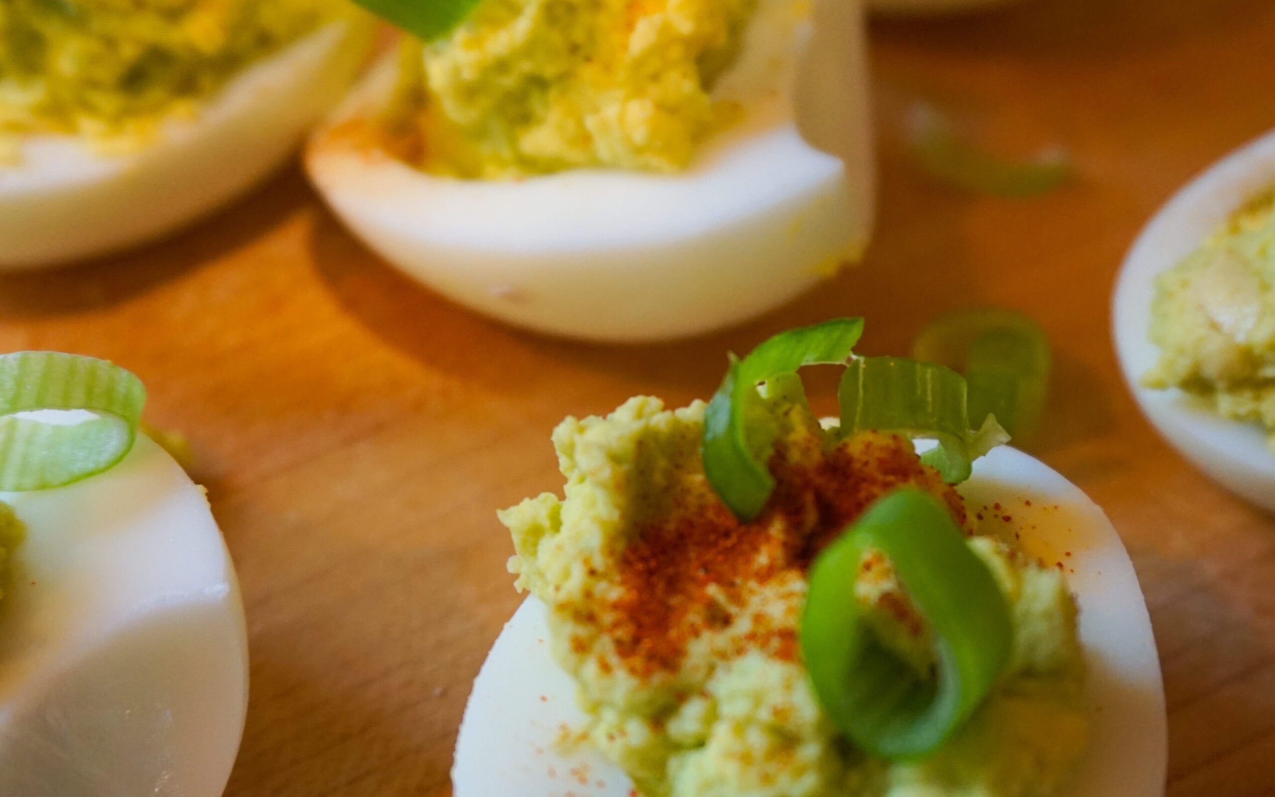 avocado filled deviled eggs laid out on wooden cutting board