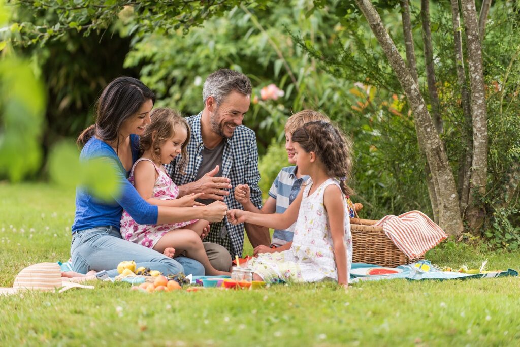 family enjoying afternoon picnic outside in the spring