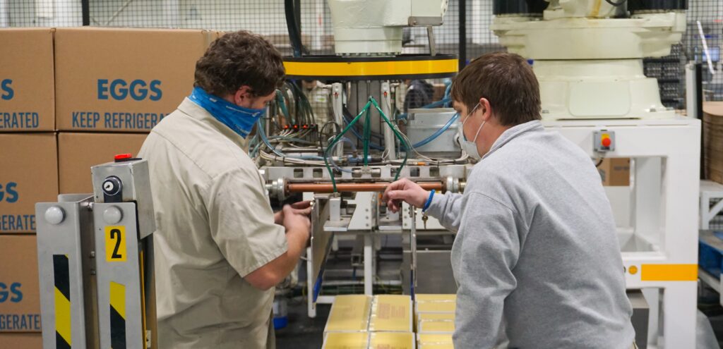 two men inspecting and fixing robotic packaging equipment