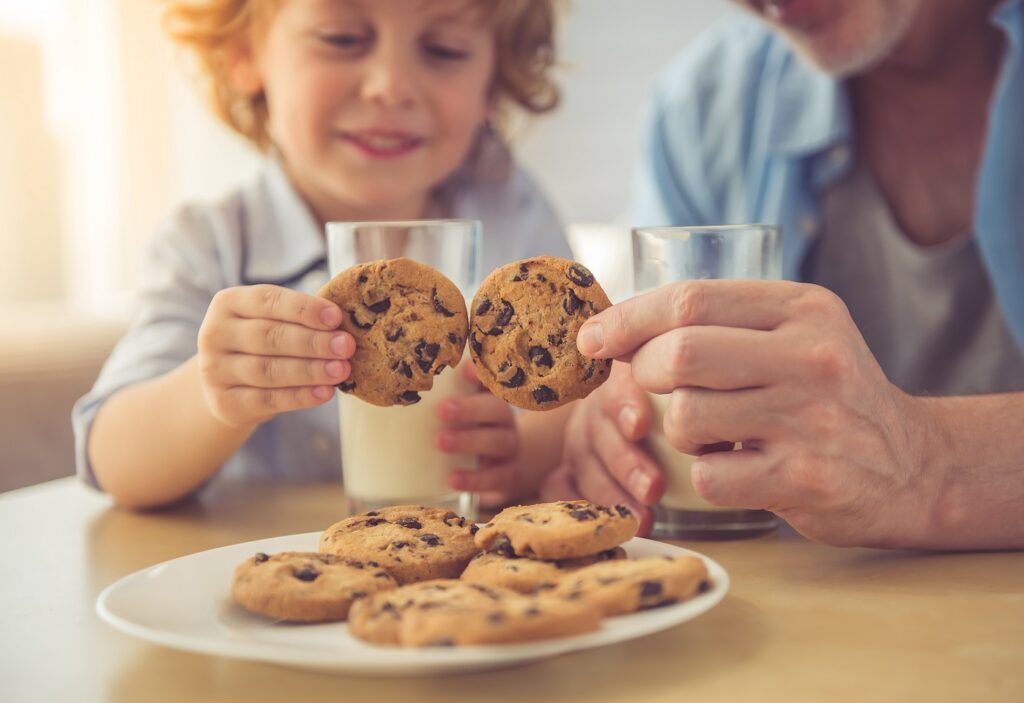 dad and son enjoying chocolate chip cookies and white milk