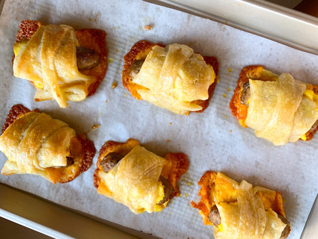 sausage, egg & cheese rolls up on parchment lined baking sheet