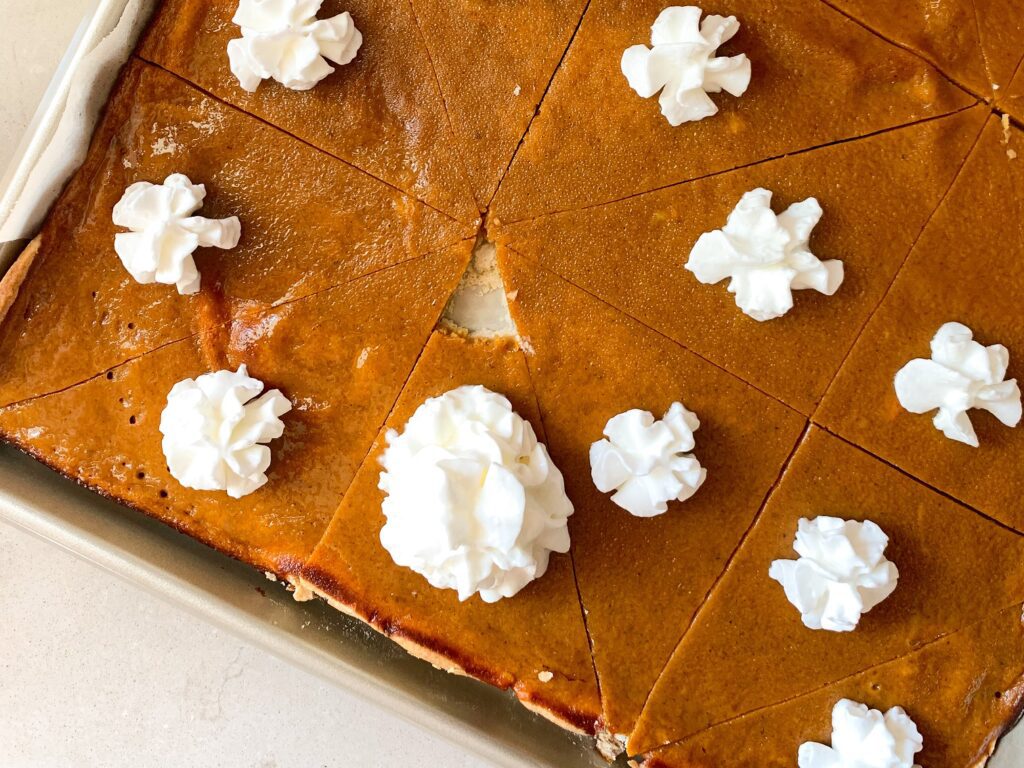 sheet pan pumpkin pie in baking tray with whipped cream